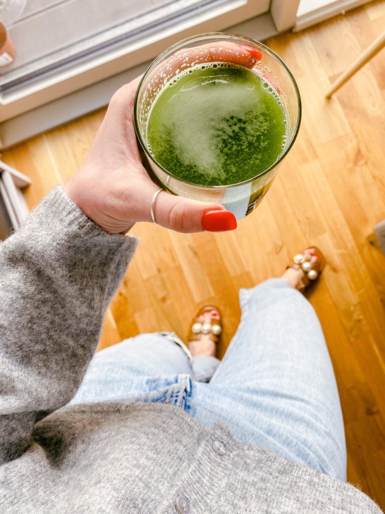green juice for clear skin and good gut health standing in morning outfit from Zara