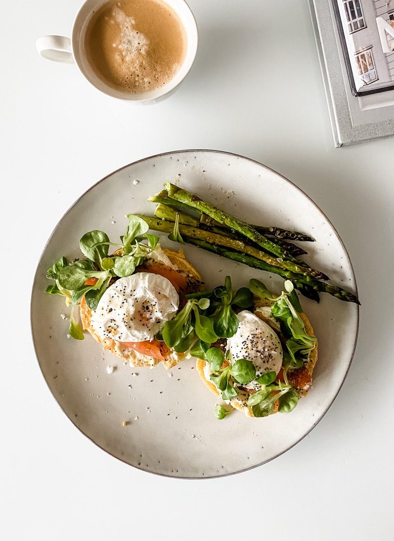 Poached egg on top of salmon and cream cheese with asparagus and a cup of coffee